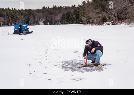 Un homme à la pêche sur glace sur l'Étang gelé à Grafton State Park dans l'État de New York. Banque D'Images