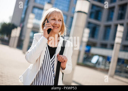 Outdoor portrait of happy senior businesswoman qui est l'utilisation de smartphone. Banque D'Images