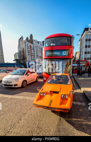 Bond Bug voiture à trois roues à Londres avec le London bus rouge derrière. La circulation de Londres. Microcar. Années 70, icône du design. Banque D'Images