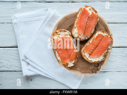 Vue d'en haut à des sandwiches au saumon fumé et fromage à la crème sur une table en bois blanc Banque D'Images