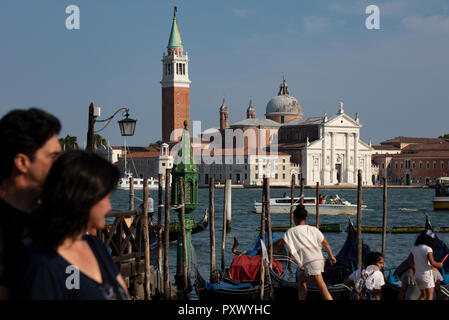 Vue de Venise vers l'île monastère de San Giorgio Maggiore. Au premier plan les touristes sont l'organisation d'une gondole et se promener le long. Banque D'Images