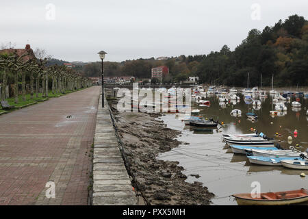 Le ria hore de Plentzia, au Pays Basque, en Espagne, au cours d'une froide journée d'hiver nuageux, avec la marée basse et les petits bateaux privés dans la boue Banque D'Images