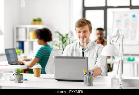 Creative male office worker with laptop Banque D'Images