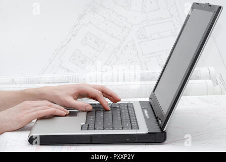 Les mains sur clavier d'ordinateur portable. Les plans d'architecture en arrière-plan. Banque D'Images