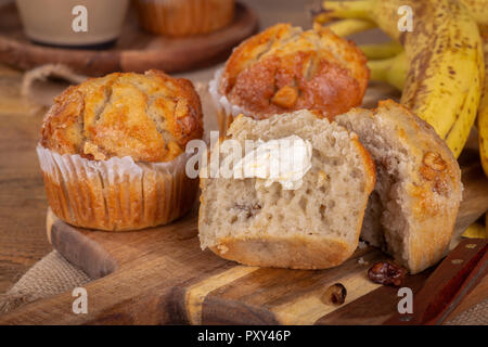 Muffins Bananes et noix coupées en deux avec du beurre et les bananes en arrière-plan Banque D'Images