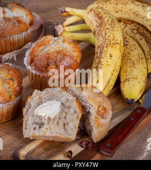 Muffins Bananes et noix coupées en deux avec du beurre et les bananes en arrière-plan Banque D'Images