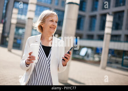 Outdoor portrait of happy senior businesswoman qui est l'utilisation de smartphone. Banque D'Images