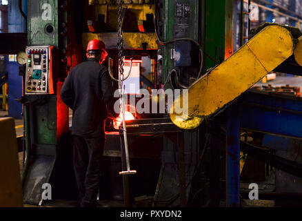 Le matriçage à chaud de haute précision, de l'automobile produit par une fabrication de processus de forgeage à chaud, ligne automatice de forgeage à chaud. Employé d'usine à prendre un échantillon de Banque D'Images