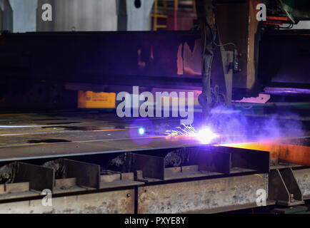 Couper le métal avec de l'équipement de plasma. Worker cutting steel pipe métal à l'aide de torche et installer une clôture en bordure de route. Cierges électriques arrière-plan. Banque D'Images