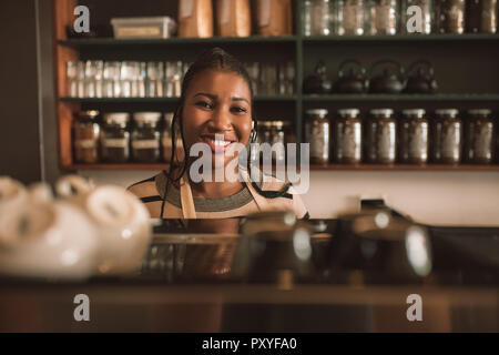 Smiling young African barista debout derrière un comptoir de café Banque D'Images