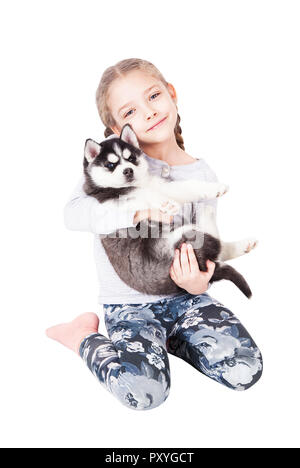 Cute little girl hugging un chiot Husky, isolé sur un fond blanc. Banque D'Images