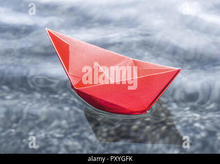 Rotes Papierschiffchen schwimmt auf Wasser Banque D'Images