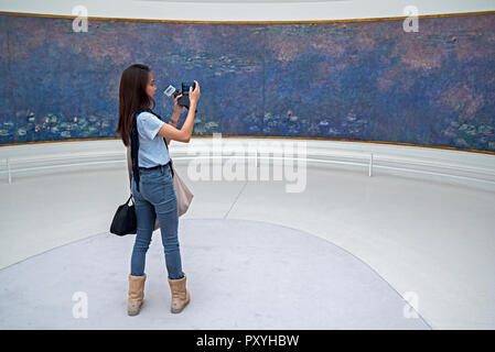 Une jeune femme prend une photo d'une partie de Monet en série nénuphar le Musée de l'Orangerie, Paris, France. Banque D'Images