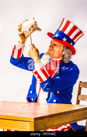 Un personnage de l'Oncle Sam tenant une tirelire et tenter de faire levier sur chaque dernier sou. Photo de conceptuel casser la banque, chaque dernier penny. Banque D'Images