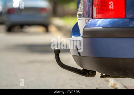 Close-up Voir le détail de la voiture bleue garée sur la rue ensoleillée, feux stop rouge et crochet pour remorque faisant glisser, de l'attelage ou la barre de remorquage sur l'espace de copie floue bac Banque D'Images