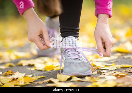 Lier les mains sur les lacets formateurs ouvrir automne, plein de feuilles jaunes. Concept photo, gros plan, horizontal Banque D'Images