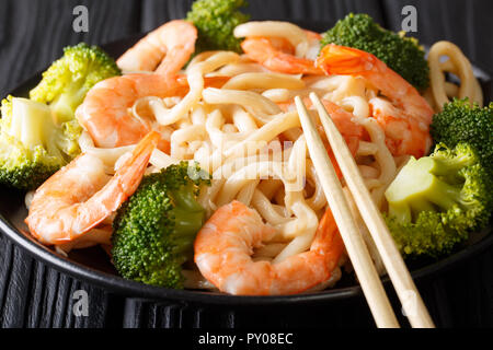 Les nouilles Udon aux crevettes et brocolis libre sur une plaque sur la table horizontale. Banque D'Images