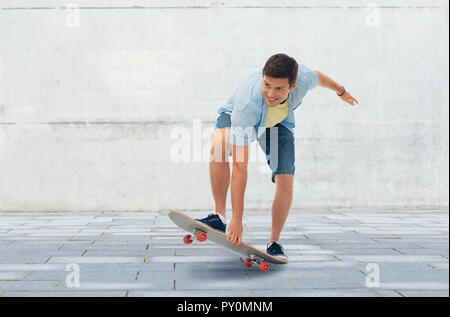 Jeune homme équitation skateboard sur fond urbain Banque D'Images