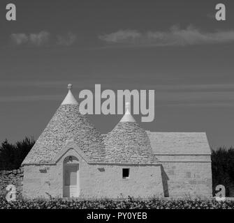 Trulli traditionnelle blanchie à la maison avec toit conique, situé à l'extérieur de Locorotondo dans la vallée d'Itria, Pouilles, Italie du Sud, en monochrome. Banque D'Images