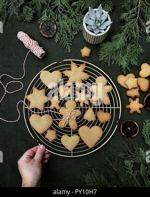 La main de femme sur une grille de refroidissement avec Noël gingerbread cookies Banque D'Images