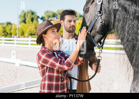 Cowboy et cowgirl dans les tenues de palming au ranch cheval noir Banque D'Images