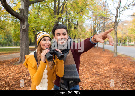 Happy young couple explorer en automne au parc avec des jumelles Banque D'Images