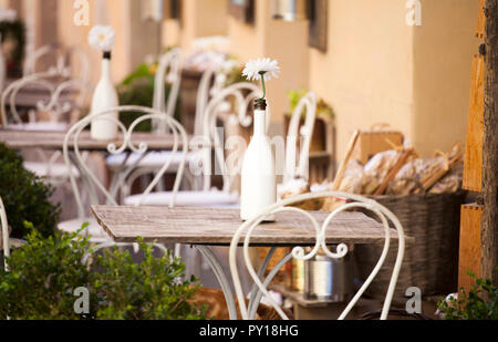 Agréable terrasse sur une rue italienne avec des chaises blanches et de fleurs blanches Banque D'Images