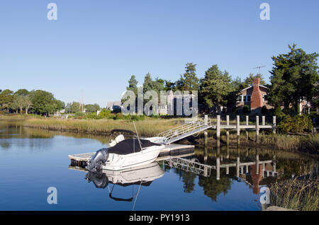 Un bateau sur un quai à une maison sur la rivière Pocasset qui mène à Buzzards Bay, Pocasset, Cape Cod, Massachusetts, USA Banque D'Images