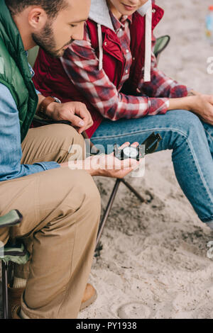 Vue partielle de couple avec boussole assis sur des chaises de camping tout en ayant Banque D'Images