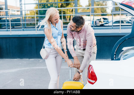 Smiling couple marié mettre une assurance en voiture sur parking Banque D'Images