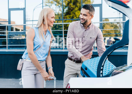 Smiling couple marié mettre une assurance en voiture sur parking Banque D'Images