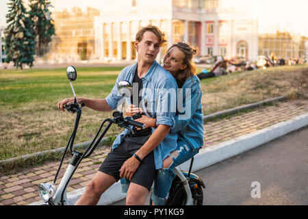 Joli jeune couple roulant vélo électrique en été Banque D'Images