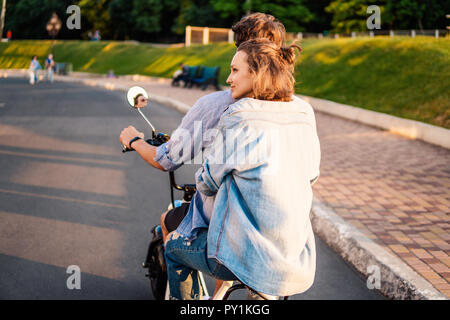 Joli jeune couple roulant vélo électrique en été Banque D'Images