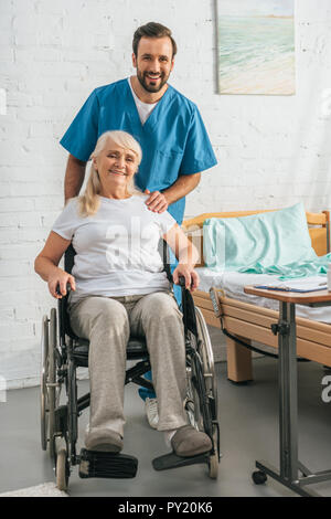 Cheerful young infirmier et happy senior woman in wheelchair smiling at camera Banque D'Images