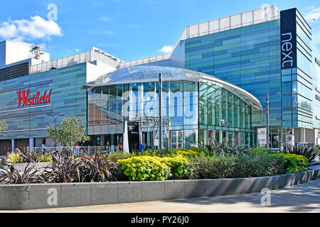 Le centre commercial Westfield London Ville Blanche d'entrée en verre à côté du bâtiment entreprise de vêtements au détail suivant façade moderne de l'Ouest design London England UK Banque D'Images