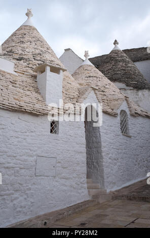 Alberobello, Italie. Au toit conique blanchis à la maison wahsed trulli derrière un mur blanc, dans la ville de Alberobello dans les Pouilles, Italie du Sud Banque D'Images