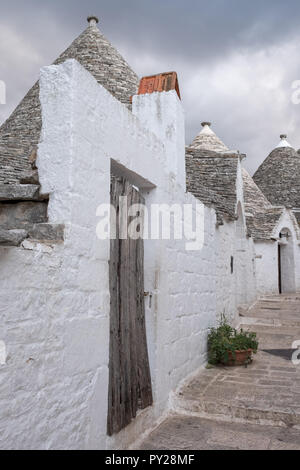 Alberobello, Italie. Au toit conique blanchis à la maison wahsed trulli derrière un mur blanc, dans la ville de Alberobello dans les Pouilles, Italie du Sud Banque D'Images