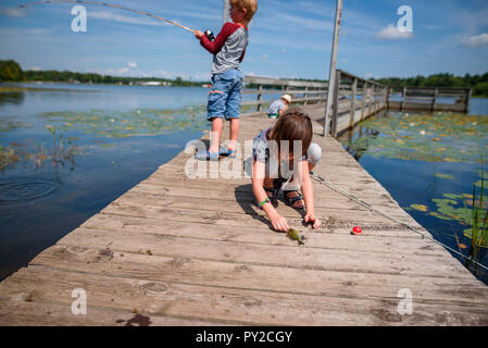 Trois enfants sur un quai de pêche en été, United States Banque D'Images