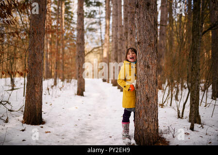 Smiling girl se cacher derrière un arbre dans les bois, United States Banque D'Images