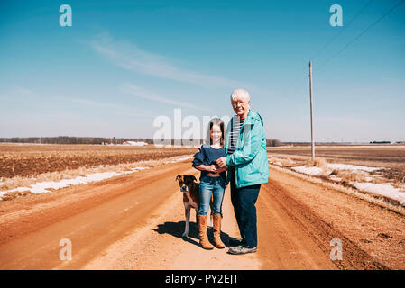 Grand-mère et sa petite-fille debout sur une route avec leur chien, United States Banque D'Images