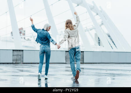 Vue arrière du young couple holding hands et de poings sur rue à jour nuageux Banque D'Images