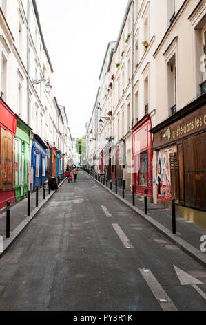 Rue claire et étroite de boutiques colorées et de magasins presque vides de gens un peuple non reconnaissable au loin, à Belleville, Paris, France Banque D'Images