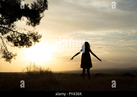 Contre-jour d'une mère et d'une fille dans une forêt de pins avec ciel jaune Banque D'Images