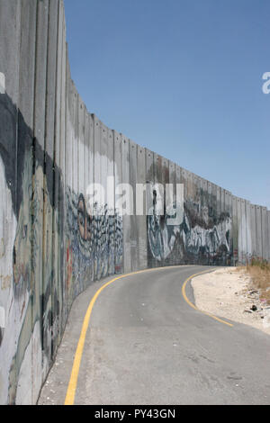 JERUZALEM, ISRAËL - JULI 11, 2004 : le long de la rue vide de haut mur de sécurité ou de séparation israélien avec la Palestine, couverts de graffitis. militant Banque D'Images