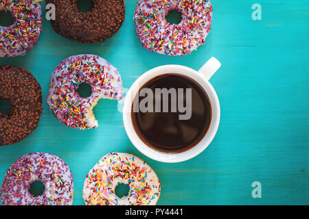 De délicieux beignets glacés et tasse de café sur la surface bleu turquoise. Mise à plat des aliments minimaliste art fond. Vue d'en haut. Banque D'Images