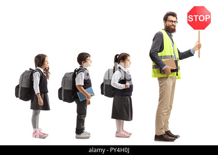 Profil de pleine longueur tourné d'écoliers en ligne derrière un enseignant avec un gilet de sécurité et un panneau d'arrêt isolé sur fond blanc Banque D'Images