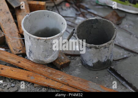 Deux seaux en chantier de construction. Deux seaux vides près de dirty utilisé des planches. Godet godet blanc et gris dans un chantier de construction. Banque D'Images