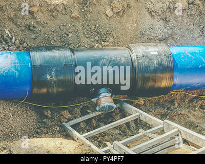 Processus de réparation de canalisation d'eau souterraine. Tubes en plastique bleu dans la tranchée soudés ensemble avec les tuyaux en plastique avec vis et co-membre de fl Banque D'Images