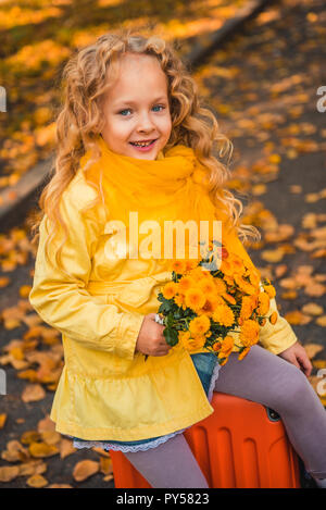 Belle petite fille aux cheveux blonds en automne fond Banque D'Images