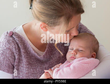 Mother holding her baby girl kissing her front close up par bébé, les yeux fermés. Banque D'Images